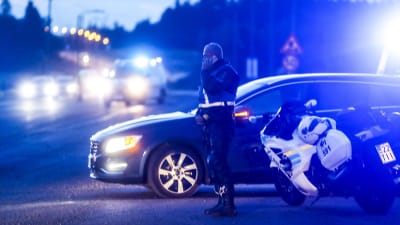 En polis står bredvid en polisbil och en polismotorcykel