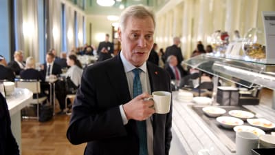 Statsminister Antti Rinne (SDP) med en kaffekopp i handen. Han står i kaféet i riksdagshuset.
