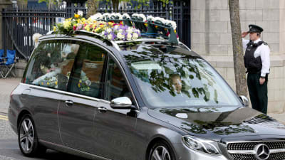 Bil med blommor på taket kör till begravning.
