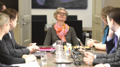 Människor förhandlar runt ett bord. Förhandlingarna leds av Vuokko Piekkala.
