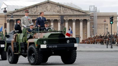 President Macron ståendes till höger uppe på fordonet.