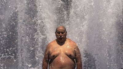 En man försöker kyla ner sig i en fontän i Portland, Oregon. 