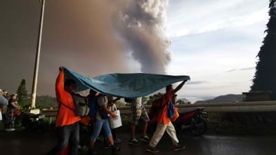 Människor i staden Tagaytay skyddar sig för askan från närliggande Taal. 