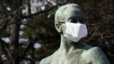 En staty som föreställer en människa har fått ett munskydd över näsa och mun.