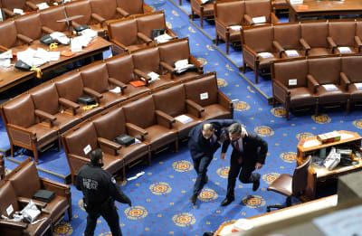 Kongressledamöter flyr undan oroligheter under kongressens session som avbröts av Trumpanhängare den 6 januari 2021 i Washington.