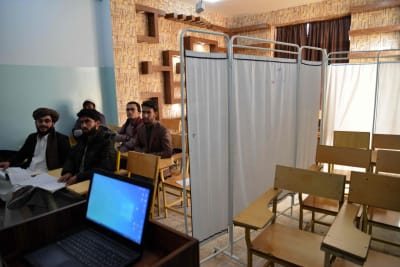 Manliga universitetsstudenter sitter i ett utrymme som delas av en gardin som skiljer män och kvinnor åt vid ett universitet i Afghanistan.