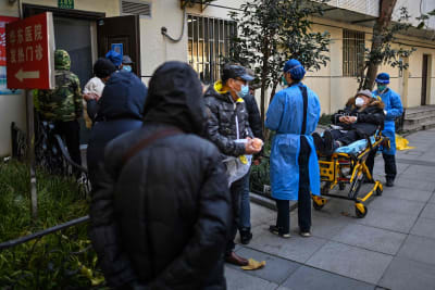 Personal i skyddskläder transporterar en patient till en feberklinik i Kina.