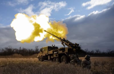 En haubits, det vill säga en slags modern kanon, avfyrar ett skott i Ukraina på ett fält.
