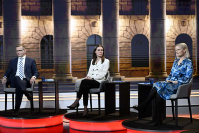 Partiledarna sitter i stolar bredvid varandra under en valdebatt, från vänster: Petteri Orpo, Sanna Marin och Riikka Purra.