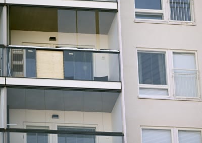 En höghusbalkong där ett bit av glasräcket täcks av en träpanel.