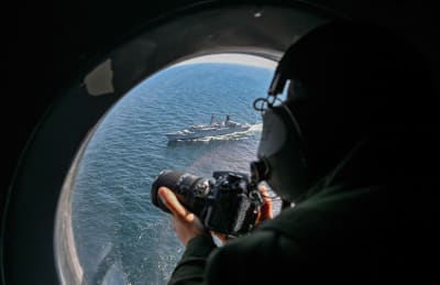 En fransk marinsoldat observerar en rumänsk fregatt från ett av fönstren på ett flygplan över Svarta havet under en militärövning.
