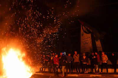 Ungdomar vid en  flammande eld på en mörk gata. 