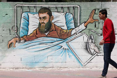 En palestinsk man passerar en väggmålning i Gaza City som föreställer hungerstrejkande Khader Adnan. 