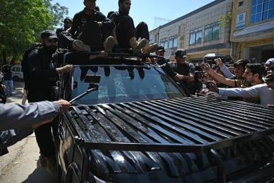 Säkerhetspersonal eskorterar en bil med Pakistans före detta premiärminister Imran Khan.