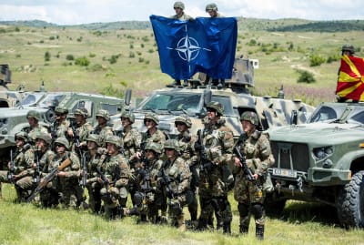 Nordmakedoniska soldater står vakt och håller upp Natoflaggan. 