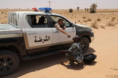 En libysk gränsvakt ger vatten till en migrant i Tunisien.