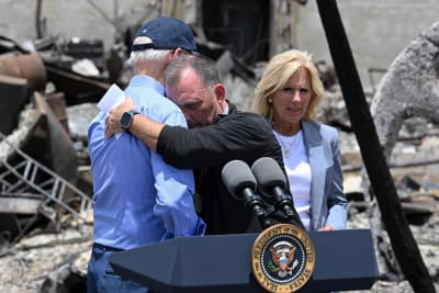 Joe Biden kramar om Josh Green vid ett talarpodium utomhus. Bredvid står Jill Biden.