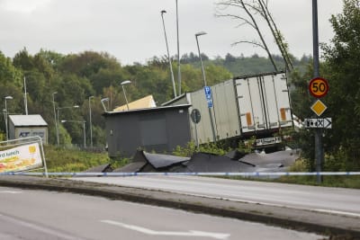 En lastbil står på snedden vid en väg som rasat. Asfalt syns sticka upp.