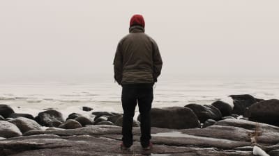 En person står ensam och tittar ut över havet.