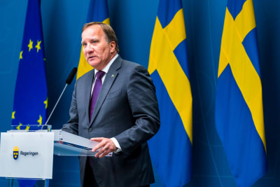 Stefan Löfven på pressträff framför EU-flagga och flera Sverigeflaggor.
