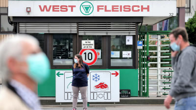 Människor i ansiktsmasker utanför livsmedelsföretaget Westfleisch i Hamm i Tyskland.