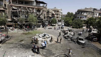 Människor besöker Tahrirtorgsdistriktet omgivet av trasiga hus där en av tre bilbomber exploderat tidigare under dagen. Åtminstone åtta människor miste livet och ett tiotal skadades i dådet den 2 juli 2017.