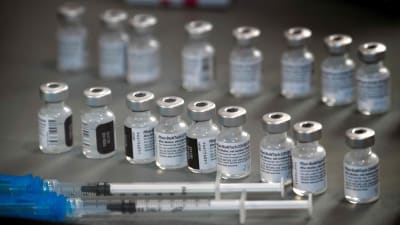 Bild på vaccindoser på rad. I förgrunden två sprutor.
