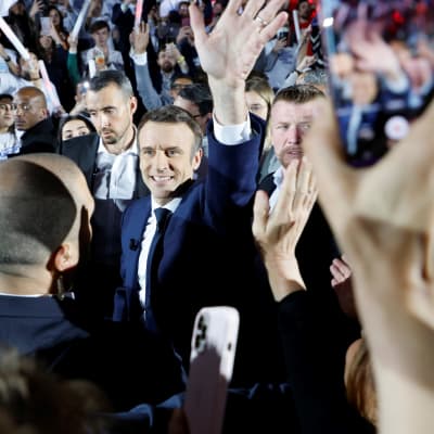 Emmanuel Macron vilkuttaa kampanjatilaisuudessa ihmisten ympäröimänä.