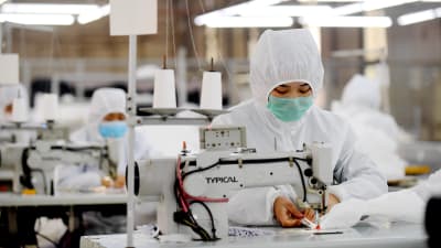 Efterfrågan på skyddsutrustning är enorm i Kina just nu. På en fabrik i Ningjin, söder om Peking, bar arbetarna själva skyddsdräkter medan de tillverkade dem. 