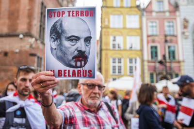 Demonstrant håller i ett plakat föreställande diktatorn Lukasjenko med blod på läpparna. Texten på skylten lyder Stop terror in Belarus.