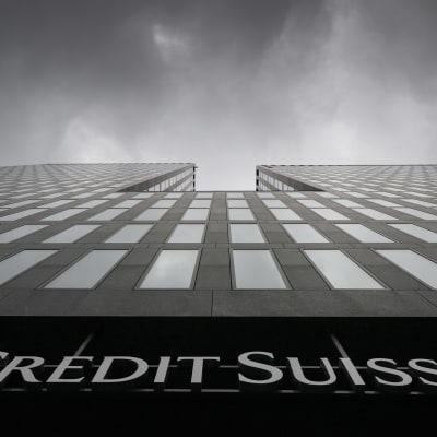 En bild av Credit Suisses gråa fasad tagen från marken med kameran riktad mot himlen. 