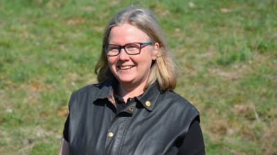 Kvinna som ser glad ut med gräs i bakgrunden.