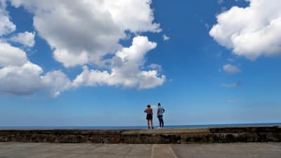 Ett par står på en mur och tittar på havet. 
