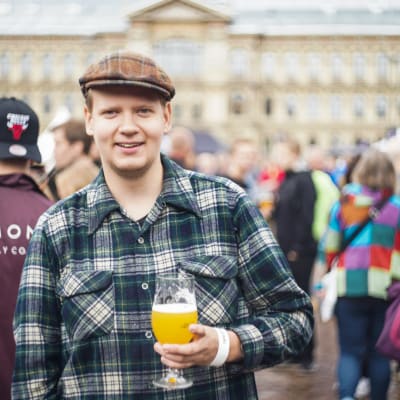 Niklas Backlund, festivalbesökare på Craft Beer Helsinki. Står med ett ölglas i vänstra handen och ser glad ut.