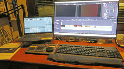Ett skrivbord med två datorskärmar och flera tangentbord. På skärmarna syns ett editeringsprojekt för video.