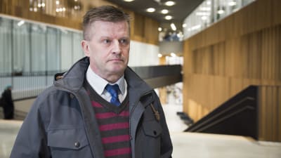 En man med kort brunt hår ser bister ut.