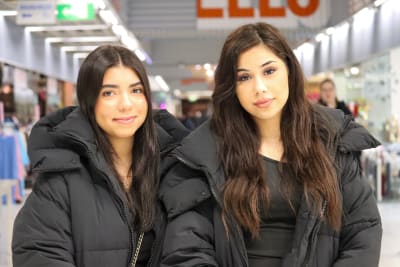 Närbild på två unga kvinnor stående i ett köpcenter. 