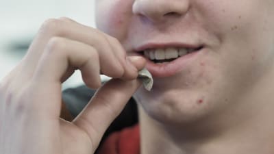 Mieshenkilö laittaa nuuskapussin huuleen