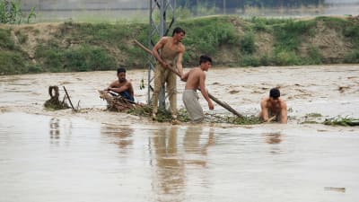 Män på en översvämmad väg i Pakistan.