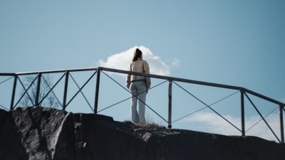 Flicka står på klippa. 