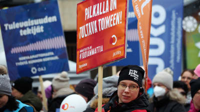 En kvinna bär på en skylt under en demonstration.