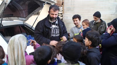 Rami Adham delar ut bananer åt barnen i Aleppo.