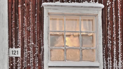Ett frostigt fönster på en röd stuga.