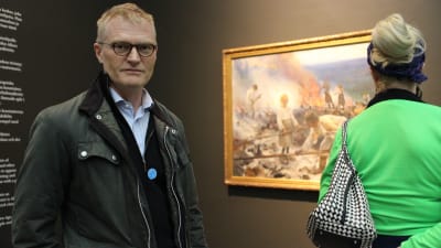Henrik Meinander och i bakgrunden Eero Järnefelts verk, Trälar under penningen.