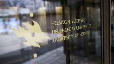 Helsingfors universitets logo på en dörr till en byggnad.