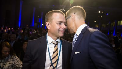 Petteri Orpo i randig slips lyssnar då Alexander Stubb talar i hans öra under Samlingpartiets partikongress i Villmanstrand.