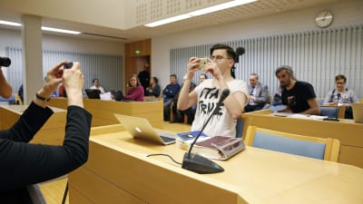 Sebastian Tynkkynen, före detta ordförande för Finsk Ungdom, i rätten åtalad för hets mot folkgrupp. Tynkkynen bad om liv för att foografera och filma rättegången.
