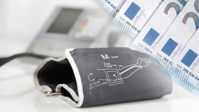 En blodtrycksmätare och ett antal 20 eurossedlar i en illustrativ bild.