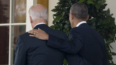 Barack Obama och Joe Biden håller vänskapligt om varandra medan de går bort från fotograferna