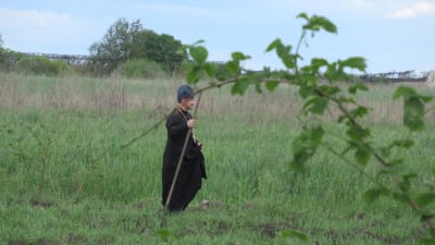 En präst vandrar på en odlingsplätt.